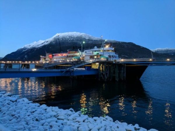 A ferry at a dock with a mountain in the background at twilight