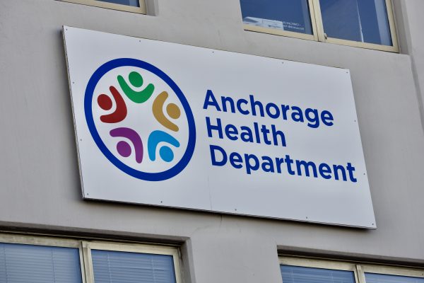 A sign on a beige wall that says "Anchorage Health Department"