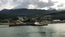 A grainy still shot from a Facebook video shows the a crane mounted on a barge-like boat colliding with a bridge as the boat passes under the bridgne