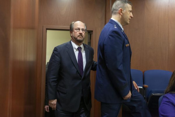 A man with a bald head walks out of a door in an office building