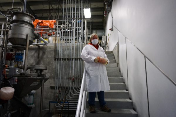 A woman in a white lab coat stands on a stairway