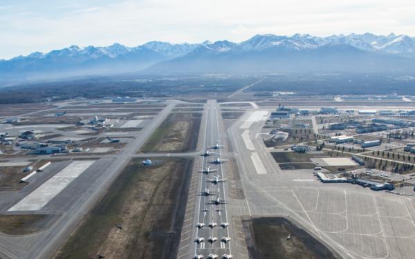 A runway with a dozen fighter jets anda mountains in the background