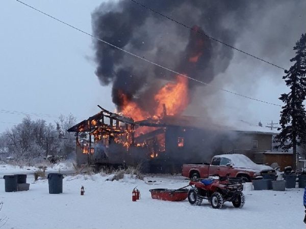 Black smoke biillows from the skeleton of a building in a snowy parea