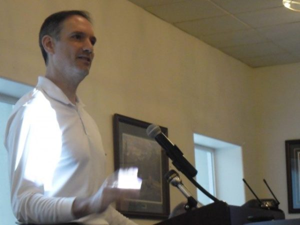 A white man speaks at a podium