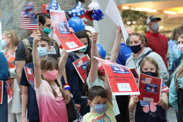 A group of people hold balloons and posters in celebration