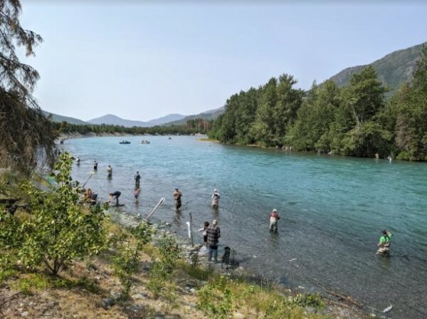 People in aders in a large river fishing with poles