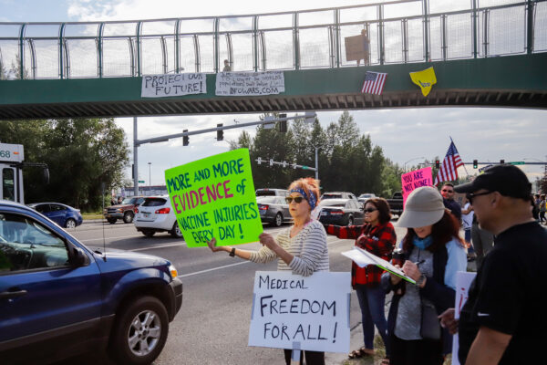 People hold signs next to a busy street