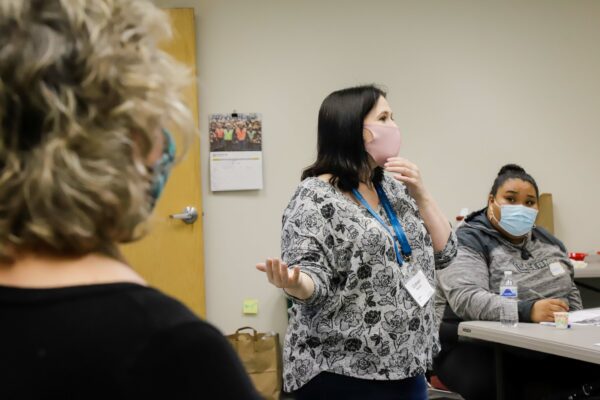 two staff from CITC lead a class on suicide intervention as a student takes notes