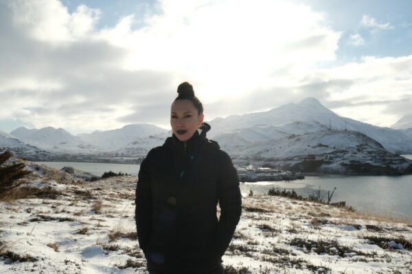 A portrait of a woman standing in a hilly, treeless Aleutian landscape