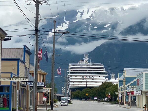 a cruise ship docks in a small town with a big mountain in the background