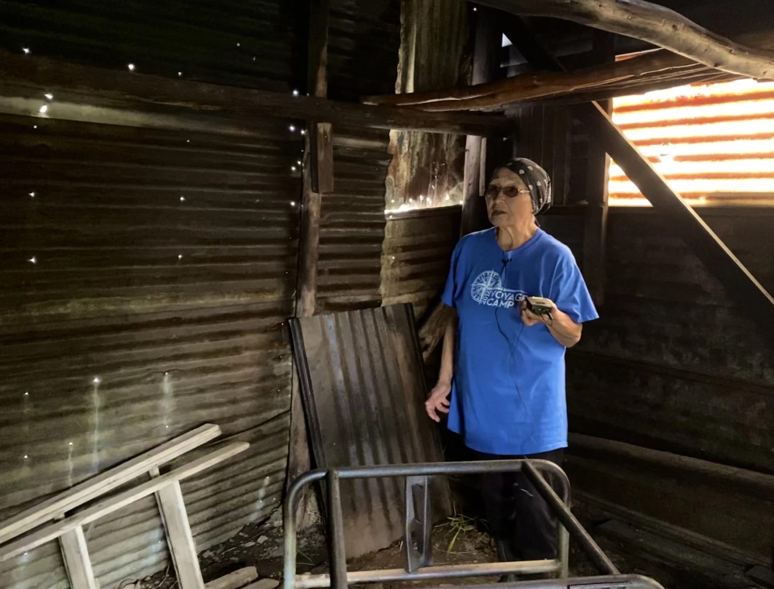 a woman in a blue shirt stands in an empty smokehouse