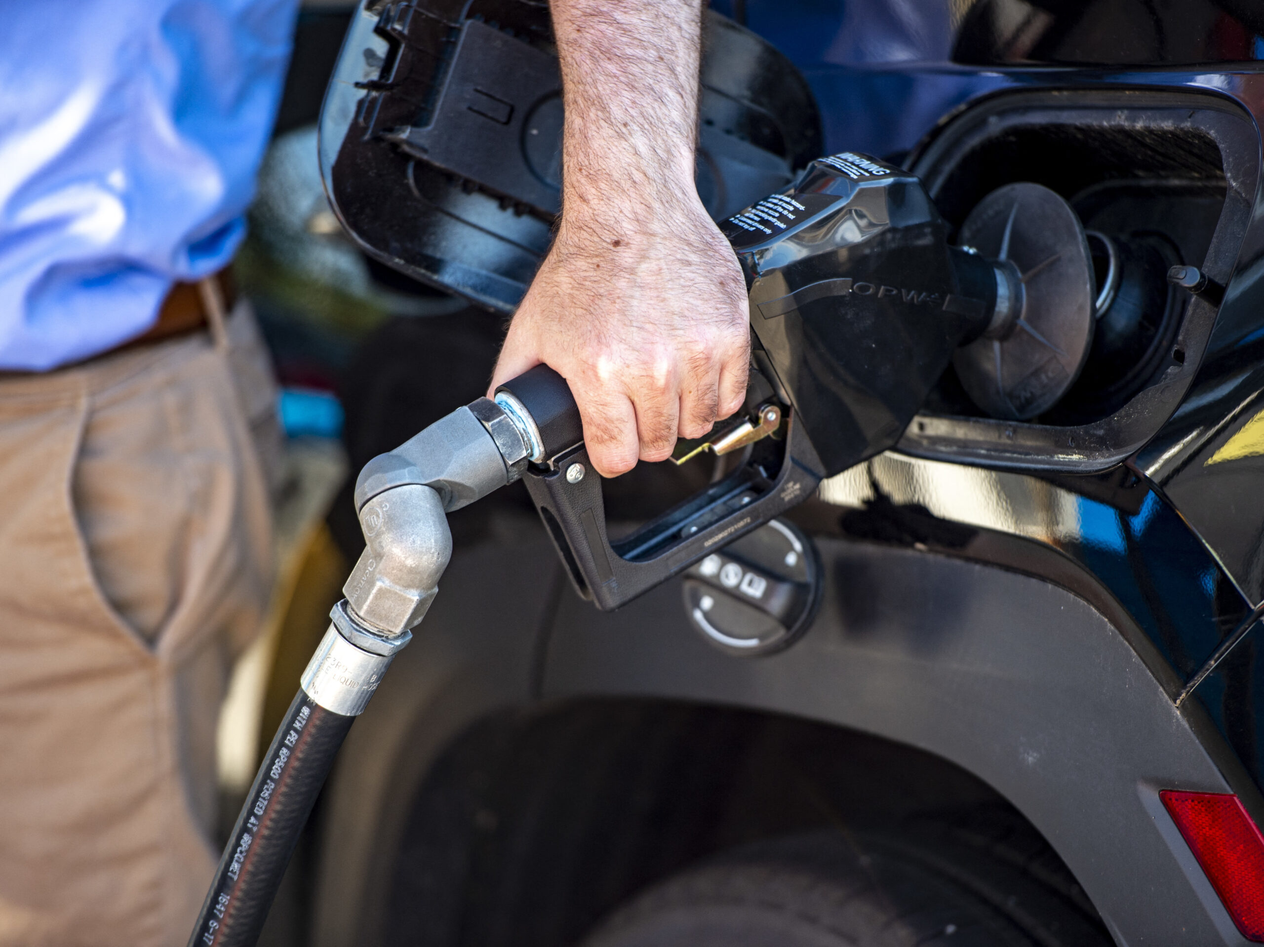a close up photo of a person's hand filling up a gas tank