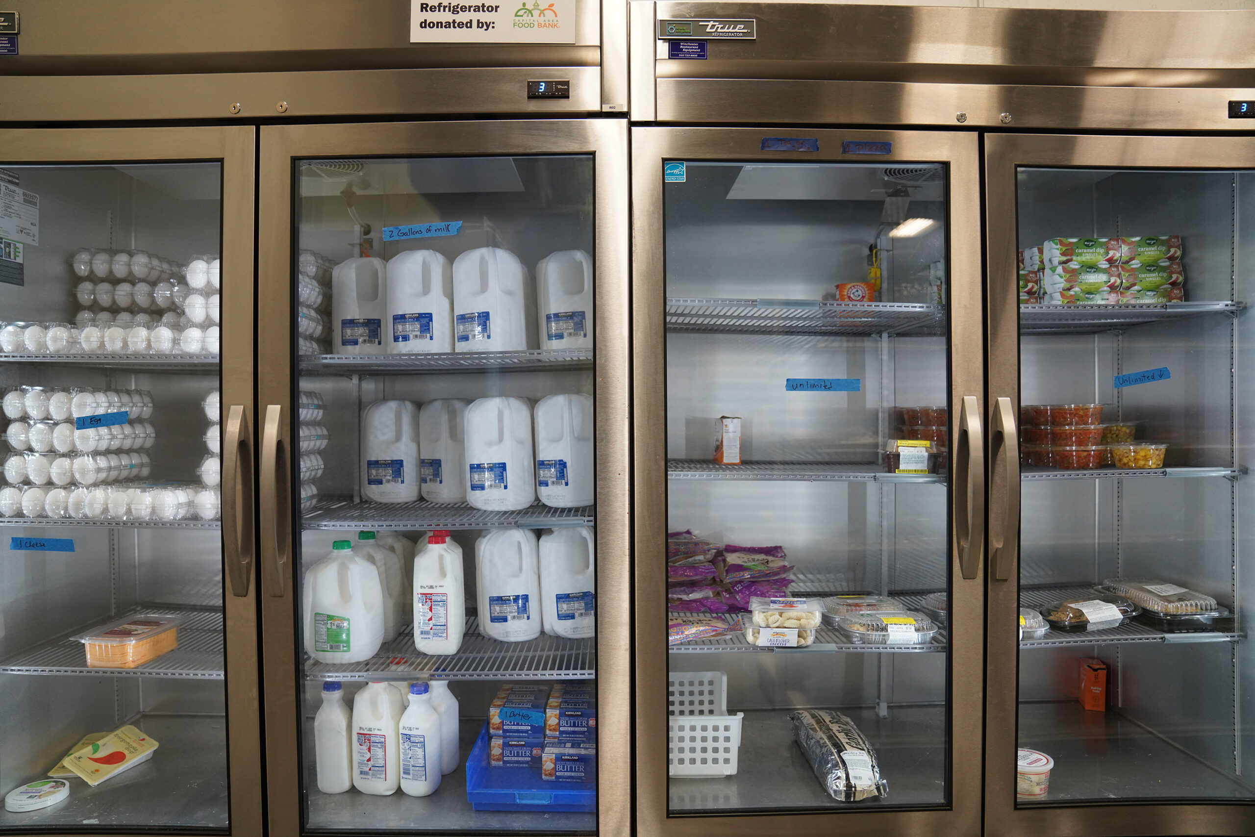 large industrial refrigerators filled with milk, eggs and other foods