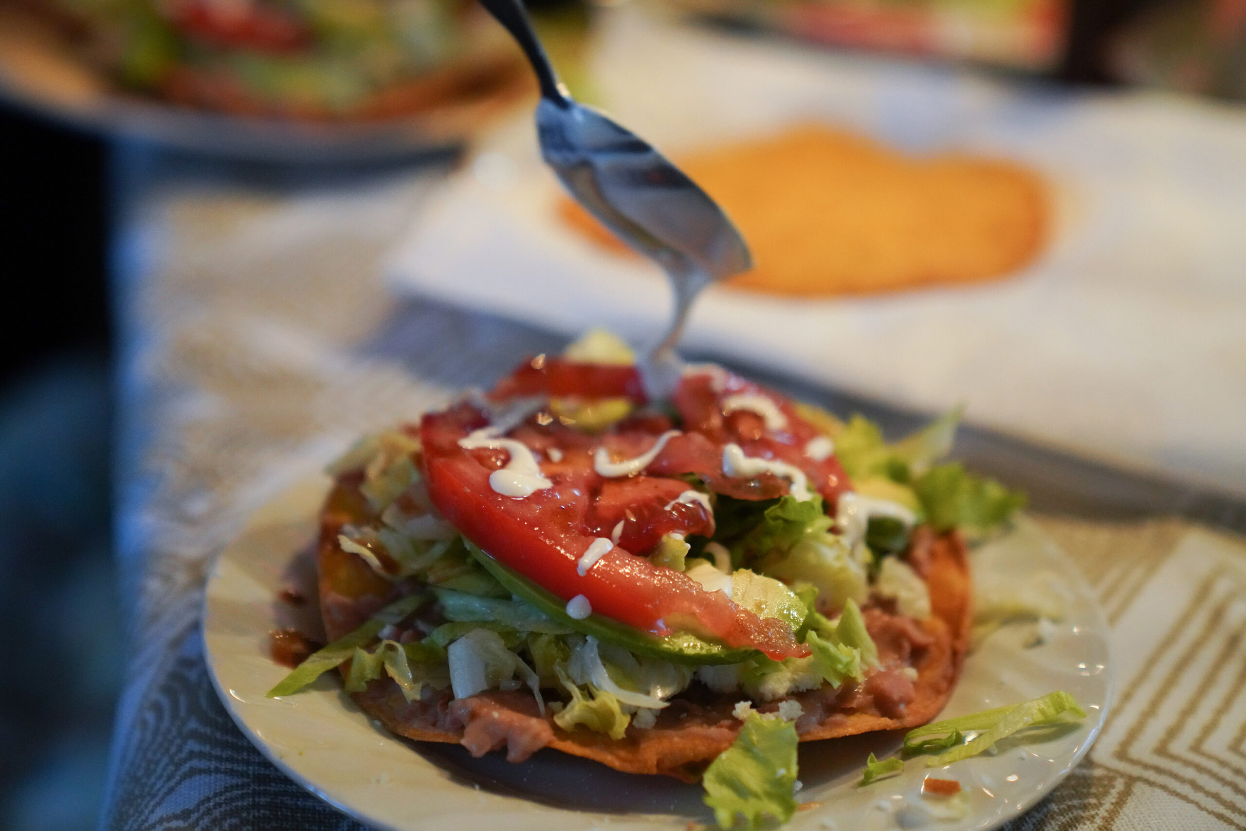 sour cream is drizzled over a tostada